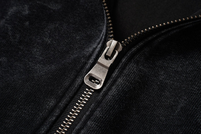 Close-up of the metal zipper slider and teeth on the black textured hoodie front