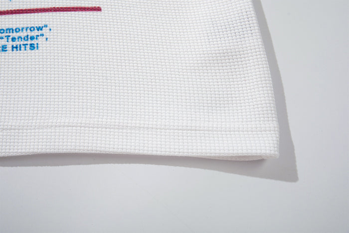 Close-up of the white waffle-textured lower hem with a partial blue and burgundy printed graphic