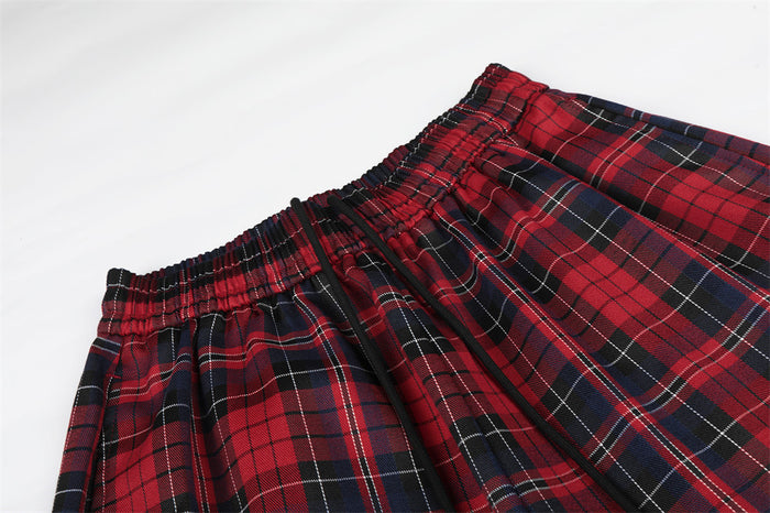 Close-up of the gathered elastic waistband and red, navy, and black plaid fabric