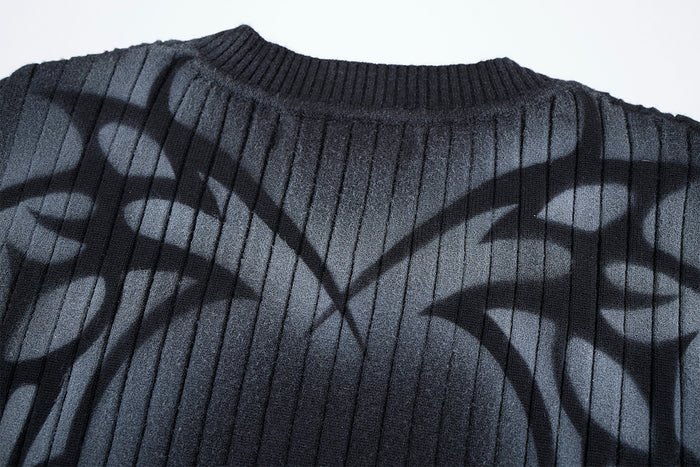 Close-up of the black ribbed sweater neckline and upper chest with an abstract gray graphic print