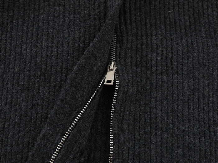 Close-up of the cardigan front showing the metal zipper teeth against the black ribbed knit
