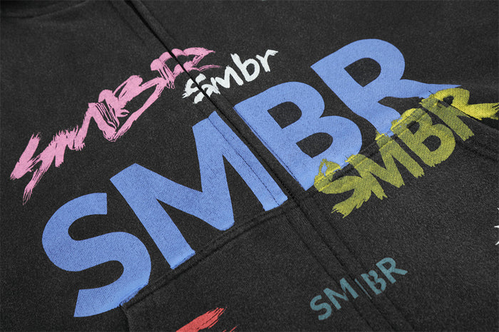 Close-up of colorful SMBR graffiti lettering in pink, blue, white, and yellow on black fabric