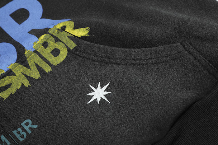 Close-up of the black hoodie upper front with yellow and blue lettering and a white star graphic