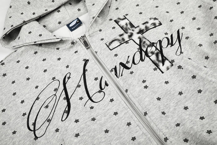 Close-up of gray star-print hoodie front showing the zipper, hood, and black script with cross graphic