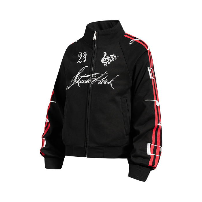 Angled front view of a black full-zip track jacket with white script and music note graphics