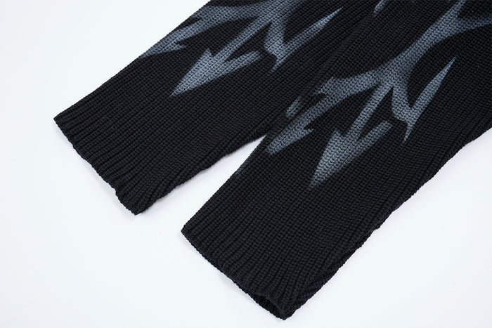 Close-up of the sweater's ribbed black cuffs featuring gray tribal flame graphics on both sleeves