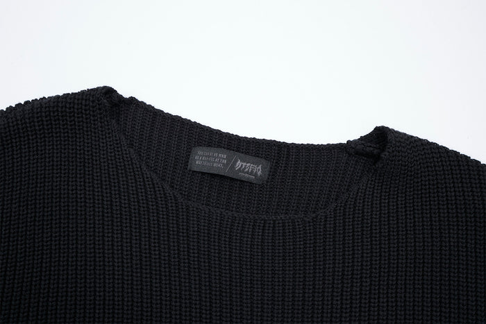 Close-up of the black sweater's ribbed crew neckline, shoulder seam, and sewn interior label