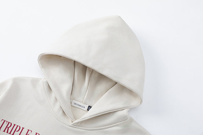 Close-up of the cream hoodie hood showing its layered interior, seams, and attached neck label
