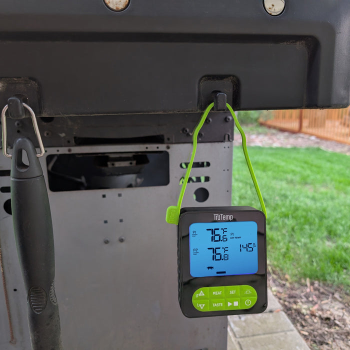 Back view of a grill with a TruTemp thermometer attached and a bright green cord hanging.