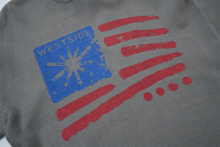 Close-up of the gray knit hoodie chest graphic with a blue panel, red stripes, and distressed texture