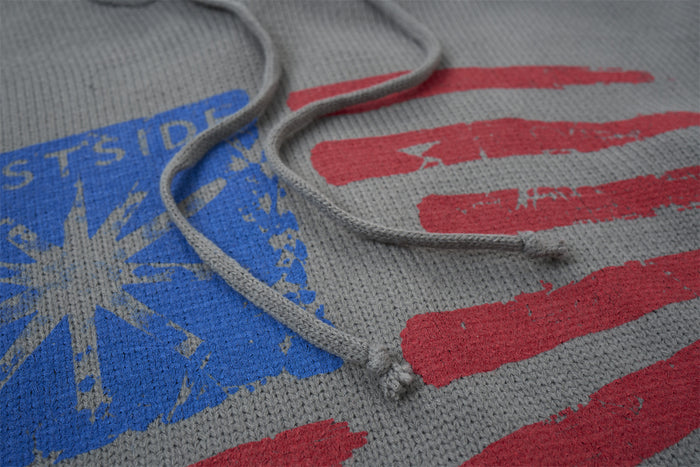Gray knitted hoodie close-up showing drawstrings, hood edge, and distressed blue and red chest graphic