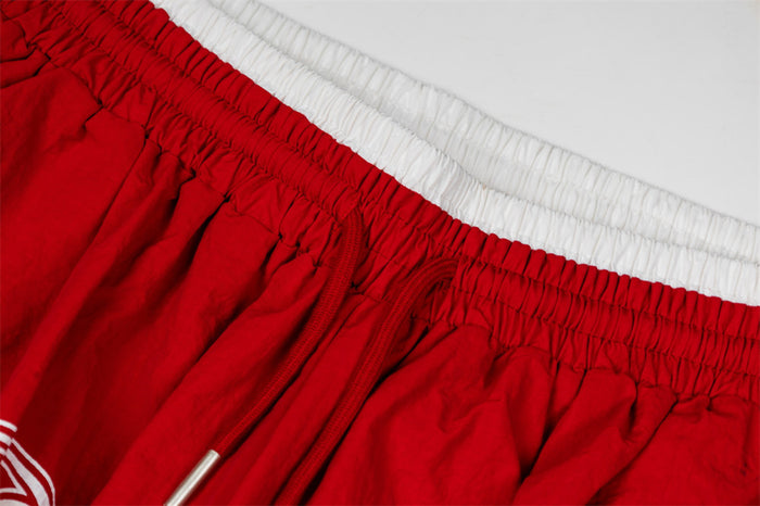 Detailed view of the red pants' gathered elastic waistband and contrasting white inner waistband
