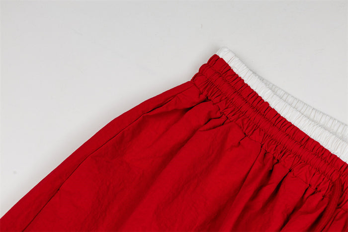 Close-up of the red pants' gathered waistband and smooth textured fabric without visible embroidery