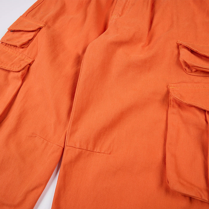Close-up of orange cargo pants showing stitched flap pockets and textured twill fabric