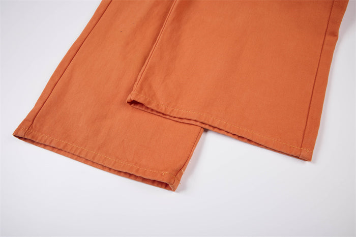 Close-up of the orange cargo pants legs showing straight stitched hems and textured woven fabric
