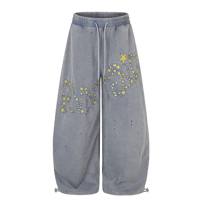 Acid-washed wide-leg sweatpants with yellow star embroidery and paint-splatter detail in blue-grey colorway