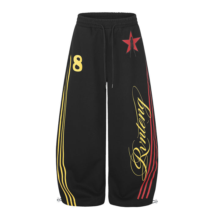 Black wide-leg sweatpants with red star graphic, yellow and red triple side stripes, and cursive script logo on the leg