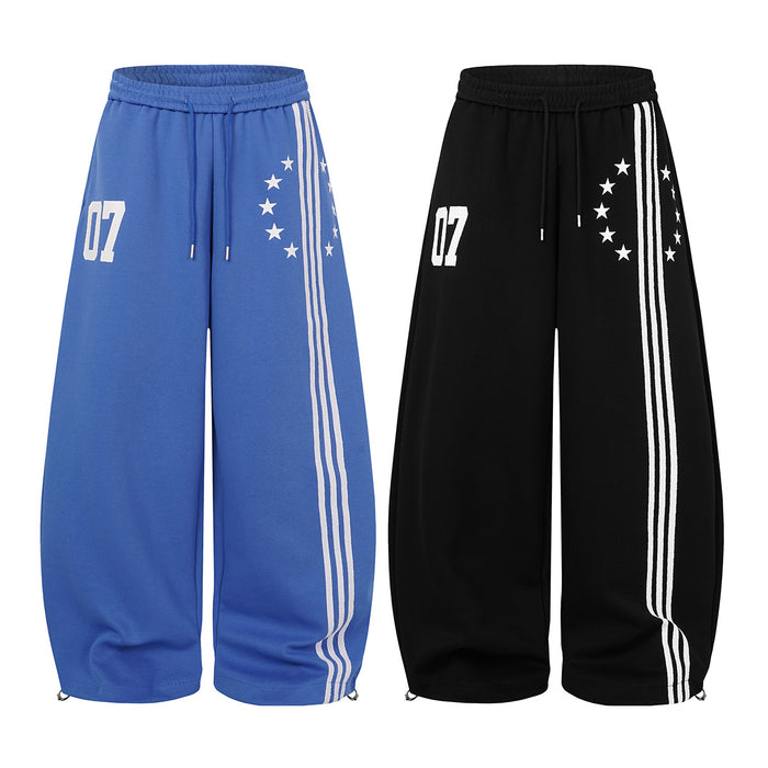Blue and black wide-leg sweatpants shown from the front with triple white side stripes, star prints and 07 graphics