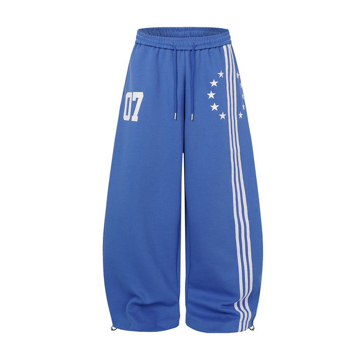 Wide-leg sweatpants in royal blue with triple white side stripes, crescent star print, and varsity 07 number graphic on the f
