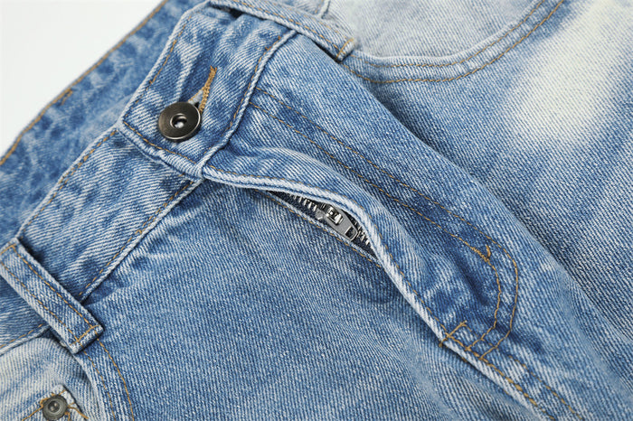 Close-up of the jeans zipper fly showing the dark metal button, zip teeth, stitching, and front pocket