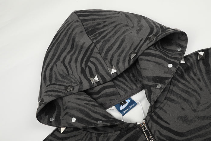 Close-up of the zebra-print hood with pyramid studs, snap fasteners, label, and front zipper