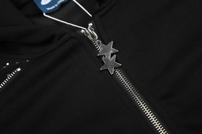 Black hoodie front zipper detail with two star-shaped pulls, rhinestone panel, and attached neck label