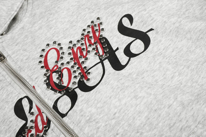 Close-up of black and red script lettering bordered by sparkling rhinestones on gray hoodie fabric