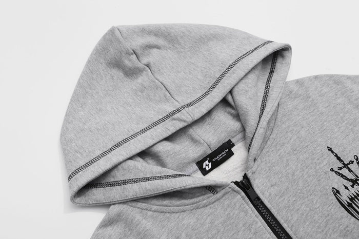 Close-up of the gray hoodie showing the lined hood, black zipper, stitched edges, and neck label