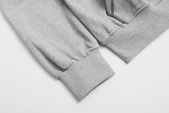 Close-up of the gray hoodie sleeve with a gathered ribbed cuff beside the ribbed lower hem